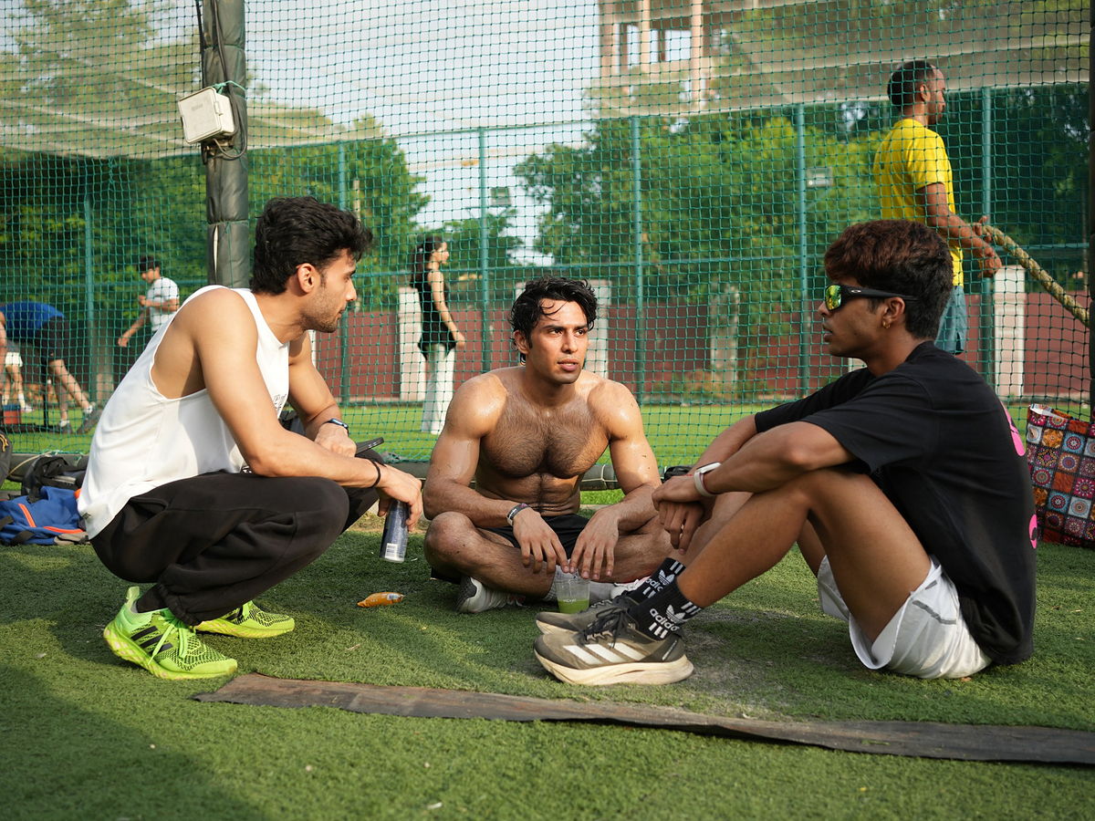 Three participants sit talking on the turf between rounds at the Jaipur pilot.